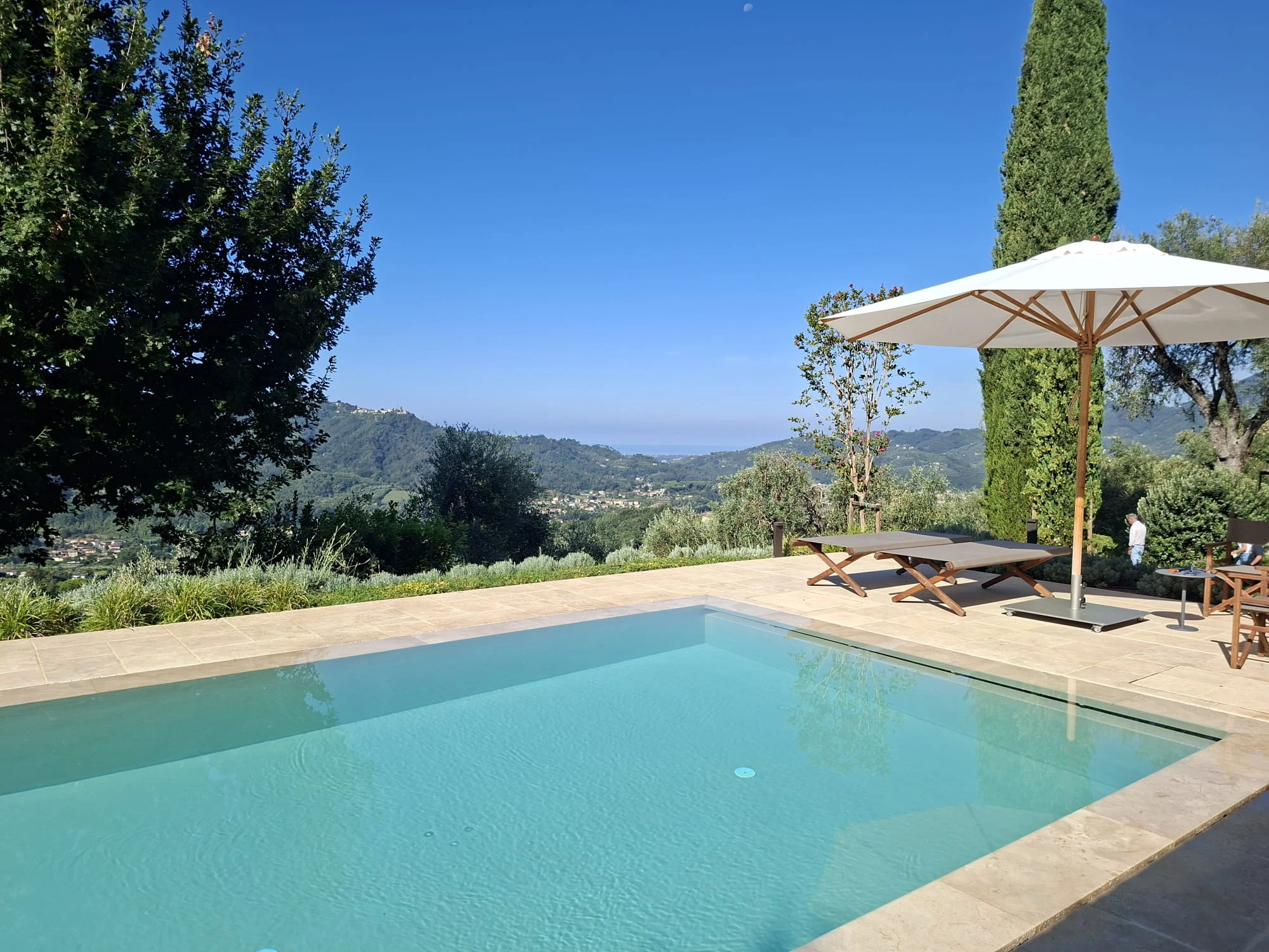 Piscina a sfioro con lettini e vista sulle colline verso il mare della Versilia