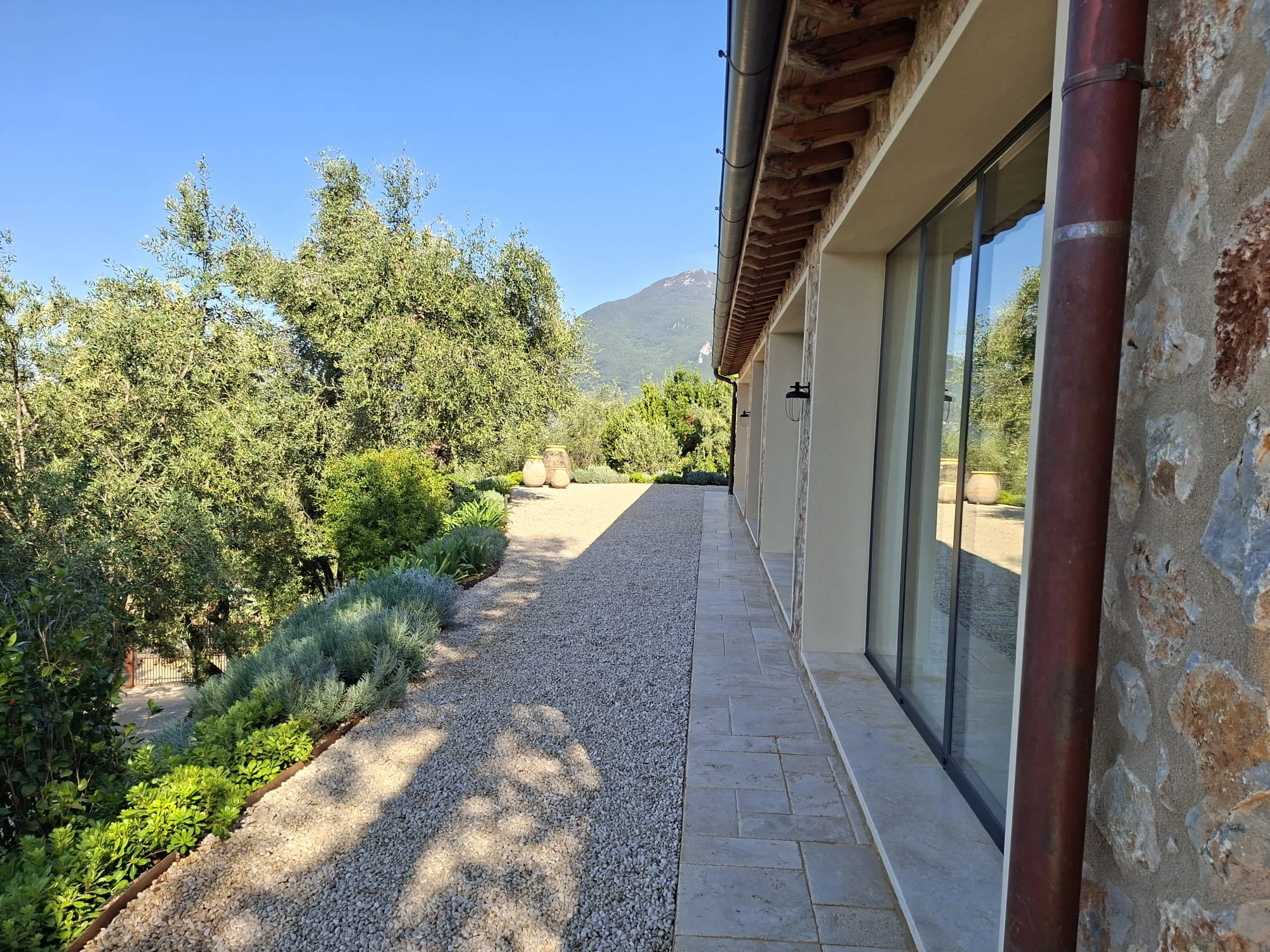 Terrazza pavimentata lungo la villa con giare in cotto e vista sulle colline